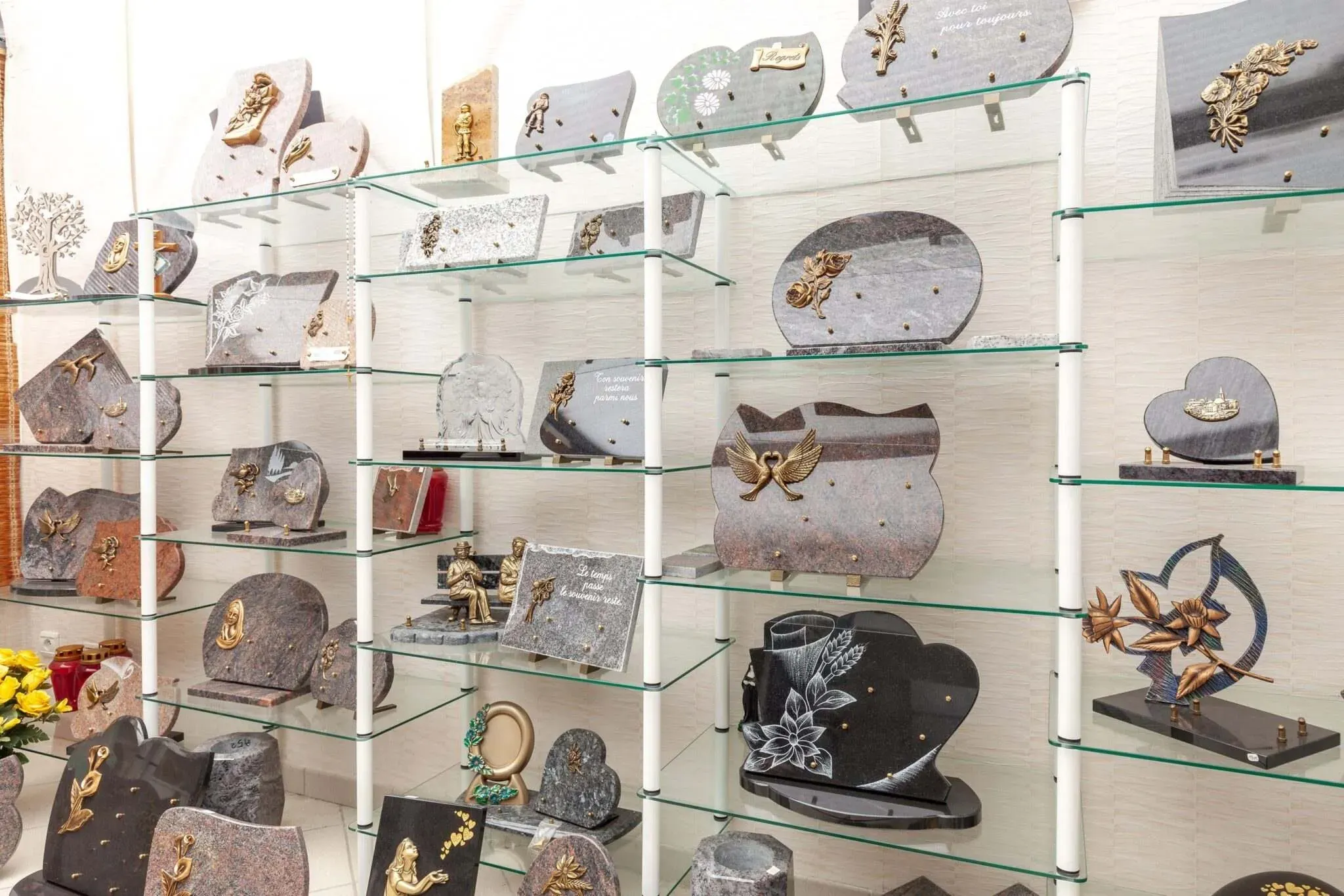 Étagères en verre présentant une collection de plaques funéraires personnalisées en granit.