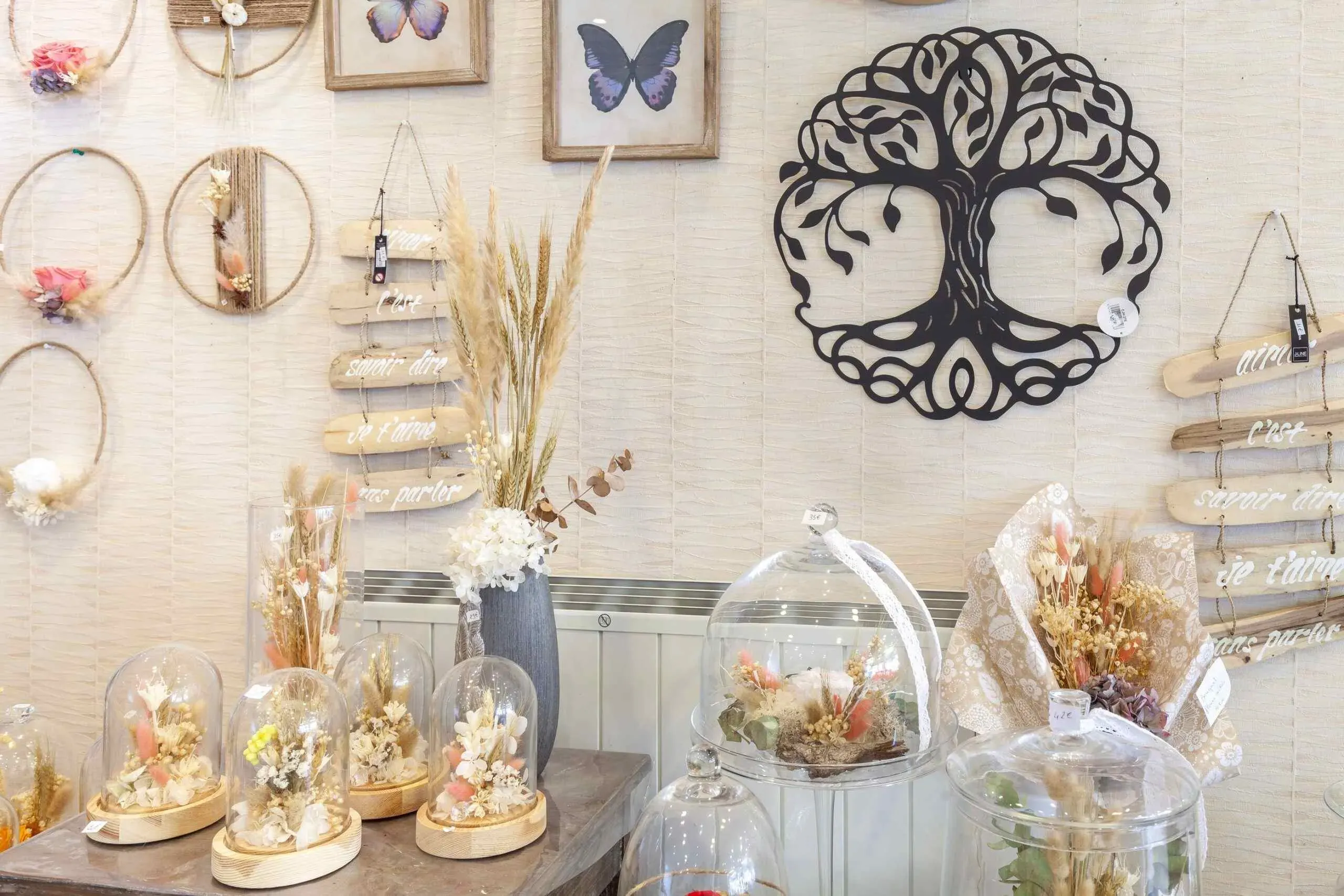 Décorations et compositions de fleurs séchées sous cloche de verre dans une boutique funéraire.