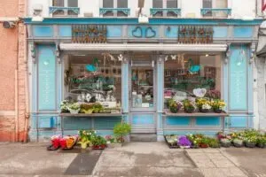 Boutique d'une agence de pompes funèbres avec de nombreuses fleurs exposées à l'extérieur.